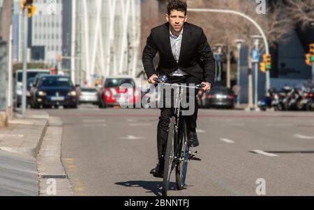 Bürger in Anzug fährt ein Fahrrad entlang einer Straße der Stadt Stockfoto