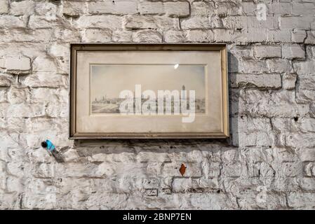 In einer Werkstatt hängt ein Bild an einer schmutzigen Wand. Stockfoto