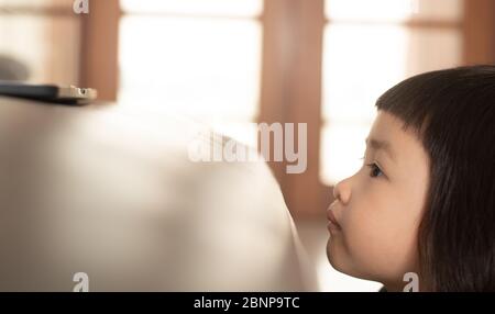 Asiatische Mädchen beobachten eine unheimlich Cartoon online von einem Notebook-Computer, die einen Gesichtsausdruck und einen hellen Ausdruck von Angst und Sorge hat. Stockfoto