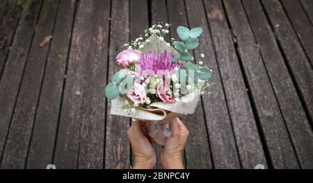 Frau mit Hand Blumenstrauß. Dunkles Holz Planken Hintergrund. Kopierbereich. Stockfoto
