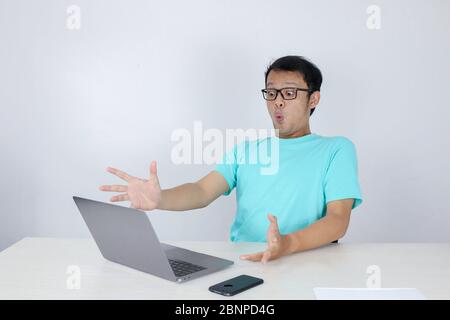 Wow Gesicht der junge asiatische Mann schockiert, was er in der Laptop sehen, wenn die Arbeit isoliert grauen Hintergrund trägt blaues Hemd. Stockfoto