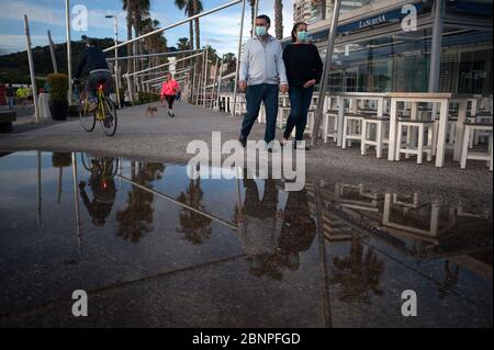 Malaga, Spanien. Mai 2020. Ein Paar, das als Vorsichtsmaßnahme Gesichtsmasken trägt, geht an einer Pfütze im Gewerbegebiet 'Muelle Uno' während der teilweisen Sperrung nach Beginn der Phase 1 in einigen Städten vorbei.Spanien durchläuft den Plan der Abseilung hin zu einer 'neuen Normalität' durch entspannende Maßnahmen, die aus der COVID-19 resultieren Ausbruch. Quelle: SOPA Images Limited/Alamy Live News Stockfoto