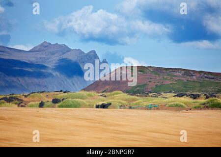 Blick über den Muschelsandstrand auf der Breidavik zum roten Vulkankrater Budaklettur und zu den Bergen der Snaefellsnes Halbinsel. Stockfoto