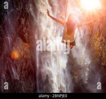 Eine Frau rockt vor einem Wasserfall Stockfoto