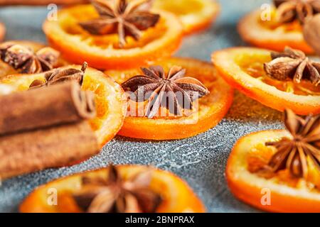 Scheiben getrockneter Orangen oder Mandarinen mit Anis und Zimt, auf blauem Hintergrund. Vegetarismus und gesunde Ernährung. Stockfoto