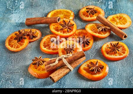 Scheiben getrockneter Orangen oder Mandarinen mit Anis und Zimt, auf blauem Hintergrund. Vegetarismus und gesunde Ernährung. Stockfoto