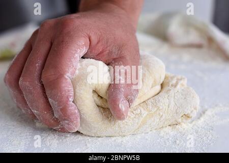 Brotherbereitungsverfahren. Nahaufnahme der Hände des Mannes Kneten Teig. Bäcker kochen Gebäck. Kulinarische Kurse und Zubereitung von Speisen. Stockfoto