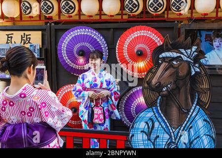 Japan, Honshu, Tokio, Asakusa, Frauen in Kimono, Die Erinnerungsfotos vor Farbenfrohen Papierschirmen Machen Stockfoto