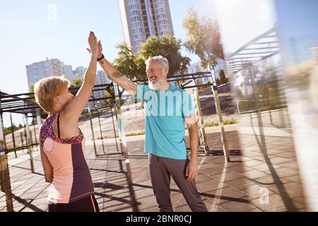 Tolles morgendliches Workout. Glücklich reifen Familie Paar geben High fünf nach erfolgreichem Training im Freien, im Alter Paar Sport zusammen Stockfoto