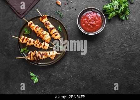 Gegrilltes Hähnchen Kebabs auf Spieße auf schwarzem Hintergrund, Draufsicht, Kopierraum. Fleisch Schweinefleisch, Huhn oder putenschisch Kebab mit Gemüse, Kräutern und Gewürzen Stockfoto