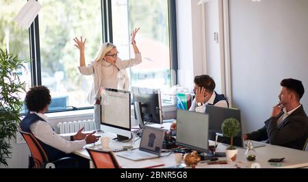 Wütender Boss, der Papiere wirft und im Büro schreit. Chef wird wütend auf Mitarbeiter. Geschäftsausfall. Stockfoto