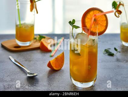 Foto von frischem Orangensaft im Glasgefäß. Sommer gesundes Bio-Getränk Konzept. Kalte Getränke mit Eis und Orangenfrüchten. Stockfoto