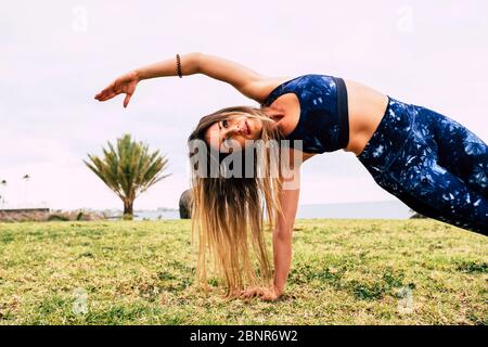 Konzept. Sport und Gewichtsverlust Übungen - junge kaukasische Frau Menschen tun Pites im Freien auf der Natur grün. Gras allein - perfekte Körper und ausgewogene Position Stockfoto