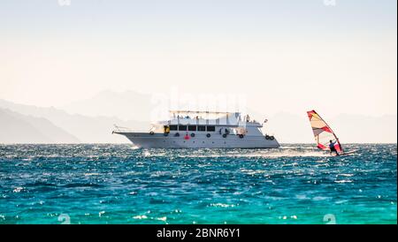 Big Boot und ein Surfer im Meer auf dem Hintergrund einer felsigen Küste in Ägypten Dahab Stockfoto