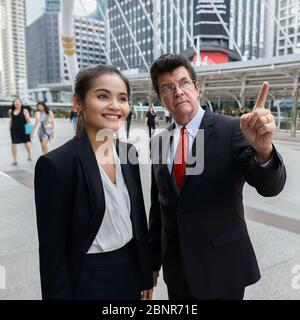 Reife Geschäftsmann Ausbildung junge asiatische Geschäftsfrau in der Stadt Stockfoto