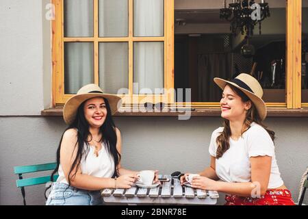 Glücklich schöne fröhliche paar Menschen junge Frauen Freunde genießen Kaffee und Cappuccino an der Fledermaus sitzen auf einem Tisch im Freien - trendige Mädchen und Freundschaft Konzept in der Freizeit Stockfoto