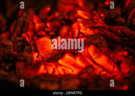 Brennen von Orangenglut aus einem Kamin, um gegrilltes Fleisch zu machen. Stockfoto