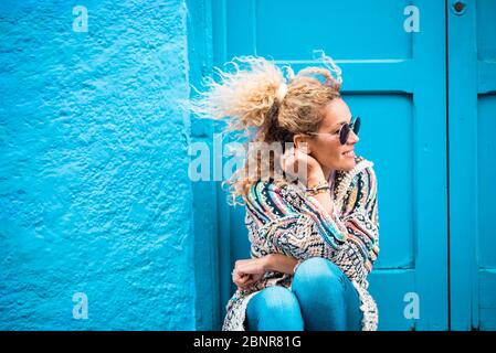 Farbige und trendige Lifestyle-Mode-Porträt von schönen jungen kaukasischen mittleren Alters Frau auf der linken Seite suchen - blau traditionellen alten Hause Hintergrund und Tür Stockfoto