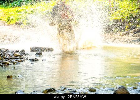 Sonniger Sommertag. Eine Menge Wasser Spray versteckt Sportler Enduro, wenn er einen Wald Bach überwindet Stockfoto