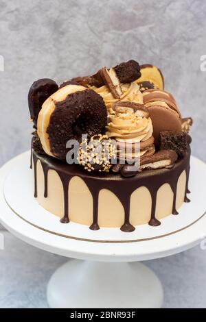Erdnussbutter-Kuchen mit geschmolzener dunkler Schokolade, Donuts, Schokoladengebiss, Cake Pops, Makronen und Süßigkeiten. Grauer Hintergrund. Stockfoto