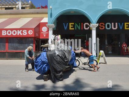 Los Angeles, Usa. Mai 2020. Ein Mann hilft einer älteren Frau mit ihren Habseligkeiten auf der Venice Beach Promenade in Los Angeles am Freitag, den 15. Mai 2020. Beamte der Stadt und des Landkreises sagten, dass die Bewohner Gesichtsbedeckungen tragen müssen, wenn sie ins Freie gehen. Die Regeln gelten "jedes Mal, wenn man draußen ist und es Menschen gibt, ob es an einem Trail Head, einem Parkplatz oder einem Bürgersteig ist", sagte Barbara Ferrer, Direktorin für öffentliche Gesundheit in Los Angeles County, am Donnerstag. Foto von Jim Ruymen/UPI Quelle: UPI/Alamy Live News Stockfoto