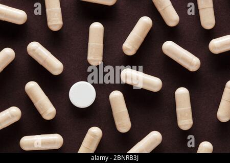 Weiße medizinische Pille sticht unter vielen anderen Kapsel Pillen. Forschung und Entdeckung des Covid-19 Virus Behandlung Medikamentenkonzept. Stockfoto