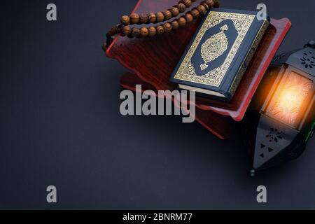 Heiliges Al Quran mit arabischer Kalligraphie Bedeutung des Al Quran, Laterne Lampe und Rosenkranz oder tasbih auf schwarzem Hintergrund. Stockfoto