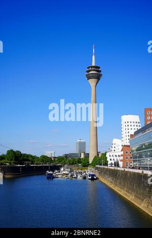 Panoramablick auf Düsseldorfs Wahrzeichen, den Rheinturm am Neuen Zollhof, Medienhafen. Gehry Gebäude auf der rechten Seite. Stockfoto