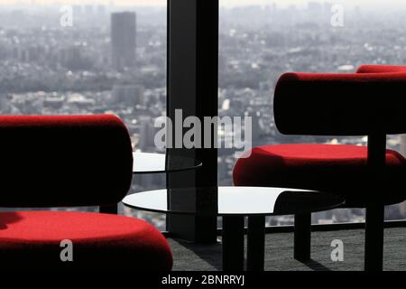 Moderner Cafétisch, der vom Fenster der Lounge eines Wolkenkratzers mit Blick auf die Stadt aufgereiht ist Stockfoto