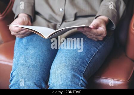 Nahaufnahme Bild der Frau Hand halten und öffnen ein leeres Notizbuch während sitzen auf Vintage-Sofa Stockfoto