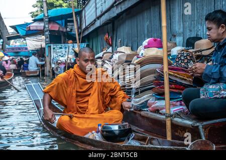 Ratchaburi, Damnoen Saduak / Thailand - 11. Februar 2020: Buddhistischer Mönch, der das Boot auf dem schwimmenden Markt von Damnoen Saduak schlingt. Der Floating-Markt ist am stärksten Stockfoto
