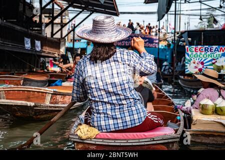 Ratchaburi, Damnoen Saduak / Thailand - 11. Februar 2020: Name dieses Ortes Damnoen Saduak Floating Market. Verkäuferin schrubbe das Boot mit ihrem Hut Stockfoto