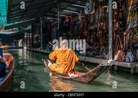 Ratchaburi, Damnoen Saduak / Thailand - 11. Februar 2020: Buddhistischer Mönch, der das Boot auf dem schwimmenden Markt von Damnoen Saduak schlingt. Der Floating-Markt ist am stärksten Stockfoto