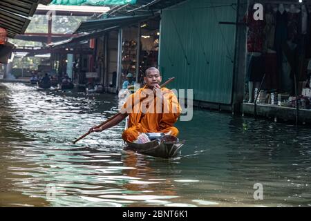 Ratchaburi, Damnoen Saduak / Thailand - 11. Februar 2020: Buddhistischer Mönch, der das Boot auf dem schwimmenden Markt von Damnoen Saduak schlingt. Der Floating-Markt ist am stärksten Stockfoto