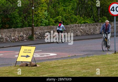 Cockenzie, East Lothian, Schottland, Vereinigtes Königreich. Mai 2020. Covid-19 Teststation: Das ehemalige Kraftwerk Cocenzie, das vom East Lothian Council von Scottish Power gekauft wurde, wird heute als Durchfahrt-Testzentrum COVID-19 eröffnet. Es wird vom Militär (51. Infanterie-Brigade) für Schlüsselarbeiter oder ein Mitglied ihrer Familie mit Symptomen betrieben. Es arbeitet als eigenständige, durchfahrbare Einrichtung - nur nach Vereinbarung - mit Personen, die während der Tests im Fahrzeug als Teil der Test-, Trace-, Isolate-Strategie der schottischen Regierung verbleiben. Radfahrer fahren am provisorischen Schild vorbei Stockfoto