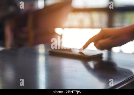Ein Finger, der auf das Mobiltelefon auf dem Tisch zeigt Stockfoto