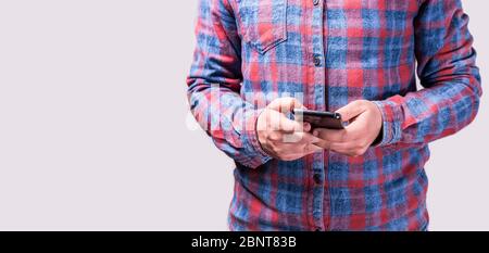 Nahaufnahme eines jungen Mannes mit einem bunten Hemd, das ein Mobiltelefon hält Stockfoto