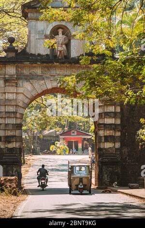 Old Goa, Indien. Auto Rickshaw oder Tuk-Tuk bewegen durch den alten Viceroy's Arch. Berühmte Vasco Da Gama Gate Wahrzeichen und historisches Erbe.Straße in S Stockfoto