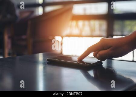 Ein Finger, der auf das Mobiltelefon auf dem Tisch zeigt Stockfoto