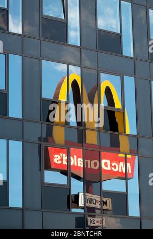 Das verspiegelte McDonald's-Logo und -Schild spiegeln das Gebäude aus Glas als ungewöhnliche, einzigartige Bildkomposition wider Stockfoto