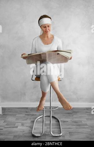 Eine sitzende Frau, die eine Zeitung liest Stockfoto