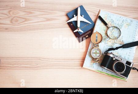 Planung einer Reise - Lupe für die Planung Reise mit Weltkarte auf dem Tisch - Pässe von zwei verschiedenen Ländern, Kamera, Spielzeugflugzeug - Preparin Stockfoto