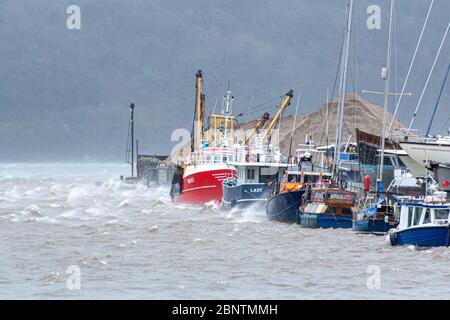 Fischerboote entlang der Hafenmauer in Port Penrhyn at Bangor in Nordwales während des Sturms Elen Stockfoto