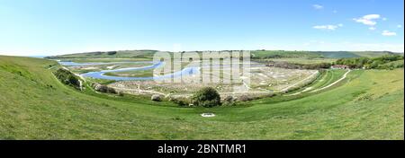 Panoramablick auf die Mündung des Flusses Cuckmere in Cuckmere Haven, wo die ikonische gewundene S-förmige Flussbiegung durch Überschwemmungsgebiete verläuft. Stockfoto