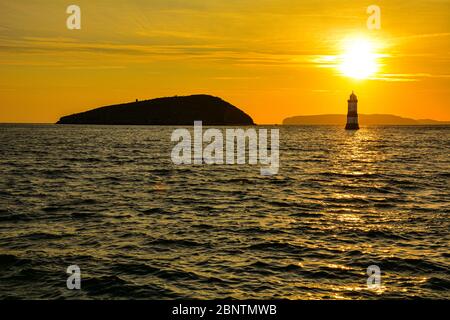 Sonnenaufgang über Puffin Island und dem Leuchtturm Trwyn Du in Penmon auf Anglesey in Nordwales Stockfoto