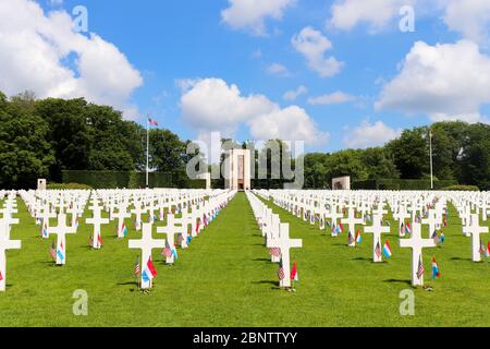 Grabsteine mit Fahnen und Blumen auf dem Luxembourg American Cemetery und Memorial Memorial Day Wochenende. Die Kapelle ist im Hintergrund. Stockfoto
