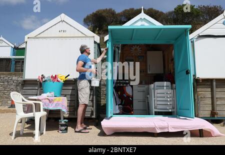 Eine Person malt ihre Strandhütte am Strand von Boscombe in Dorset, nachdem Maßnahmen eingeleitet wurden, um das Land aus der Blockierung zu bringen. Stockfoto