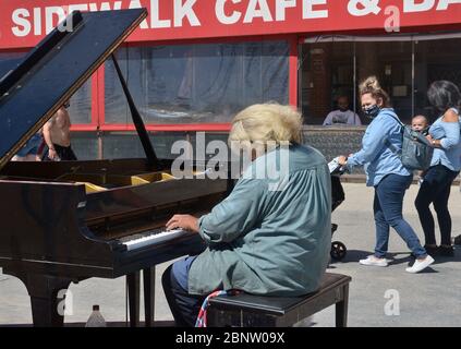 Los Angeles, Usa. Mai 2020. Strandgänger gehen am Freitag, den 15. Mai 2020, an einem Mann vorbei, der auf der Venice Beach Promenade in Los Angeles Klavier spielt. Beamte der Stadt und des Landkreises sagten, dass die Bewohner Gesichtsbedeckungen tragen müssen, wenn sie ins Freie gehen. Freizeiteinrichtungen wie Reitzentren, Tennis- und Pickleball-Plätze und Gemeinschaftsgärten, die am Freitag wiedereröffnet wurden, mit Einschränkungen wie Gesichtsbedeckungen, sozialer Distanz und Einschränkungen für Besucher. Foto von Jim Ruymen/UPI Quelle: UPI/Alamy Live News Stockfoto