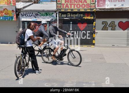 Los Angeles, Usa. Mai 2020. Radfahrer, mit und ohne Gesichtsmaske fahren am Freitag, den 15. Mai 2020 auf der Venice Beach Promenade in Los Angeles. Beamte der Stadt und des Landkreises sagten, dass die Bewohner Gesichtsbedeckungen tragen müssen, wenn sie ins Freie gehen. Die Regeln gelten "jedes Mal, wenn man draußen ist und es Menschen gibt, ob es an einem Trail Head, einem Parkplatz oder einem Bürgersteig ist", sagte Barbara Ferrer, Direktorin für öffentliche Gesundheit in Los Angeles County, am Donnerstag. Foto von Jim Ruymen/UPI Quelle: UPI/Alamy Live News Stockfoto