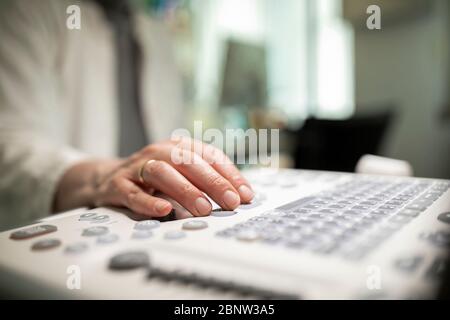 Nahaufnahme eines Technikers, der ein Ultraschallgerät in einer Klinik betreibt. Stockfoto